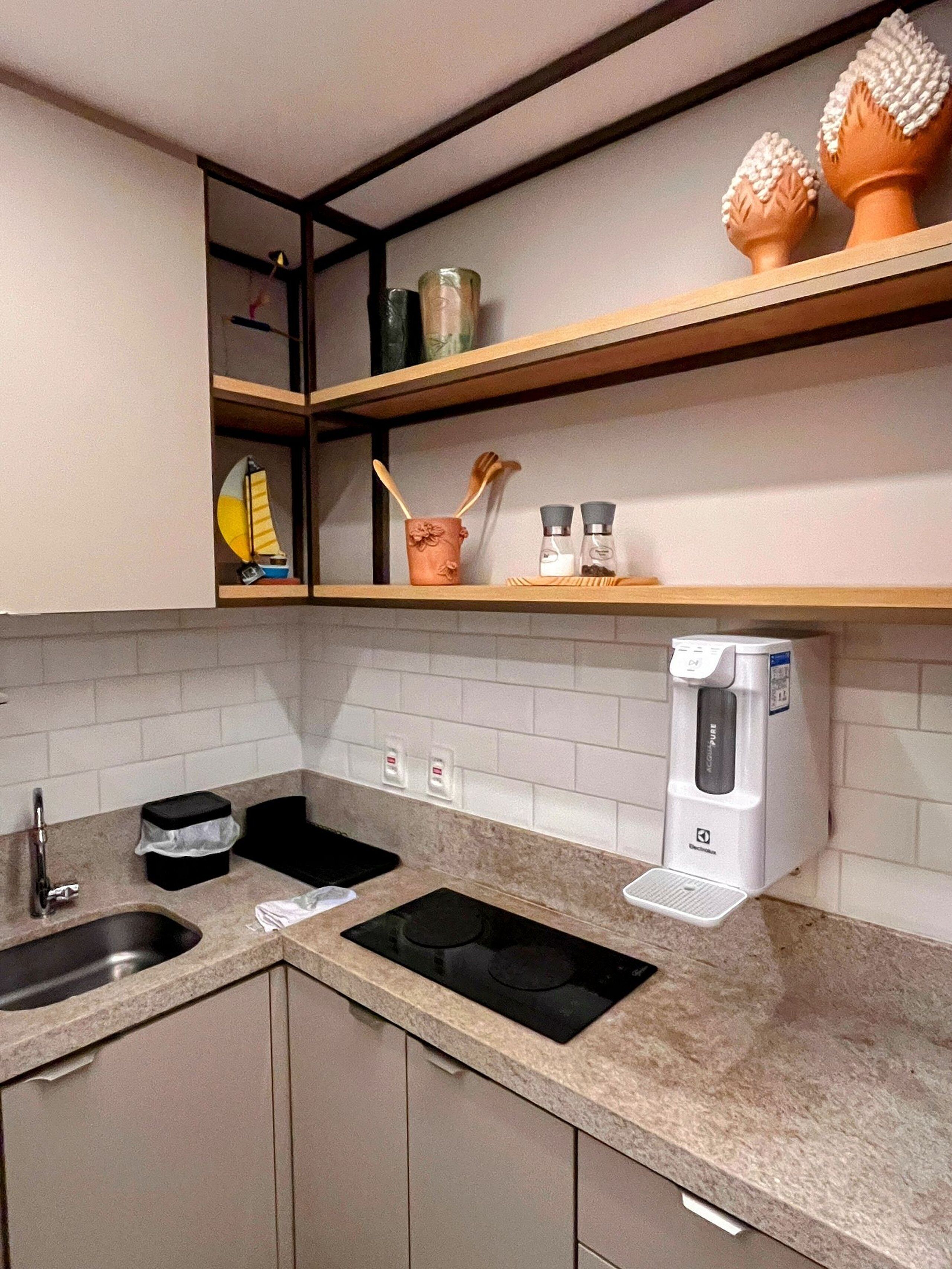 A kitchen with two sinks, a coffee maker, and wooden shelves above.