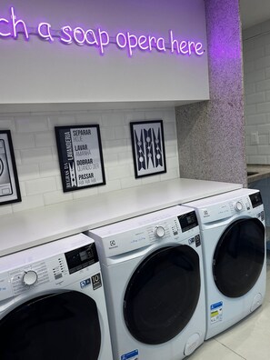 Une laverie équipée de plusieurs machines à laver et surmontée d'une enseigne au néon.