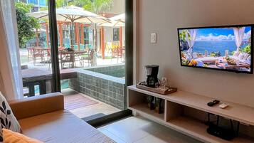 A modern hotel room with a large TV, comfortable seating, and a view of the outdoor area.