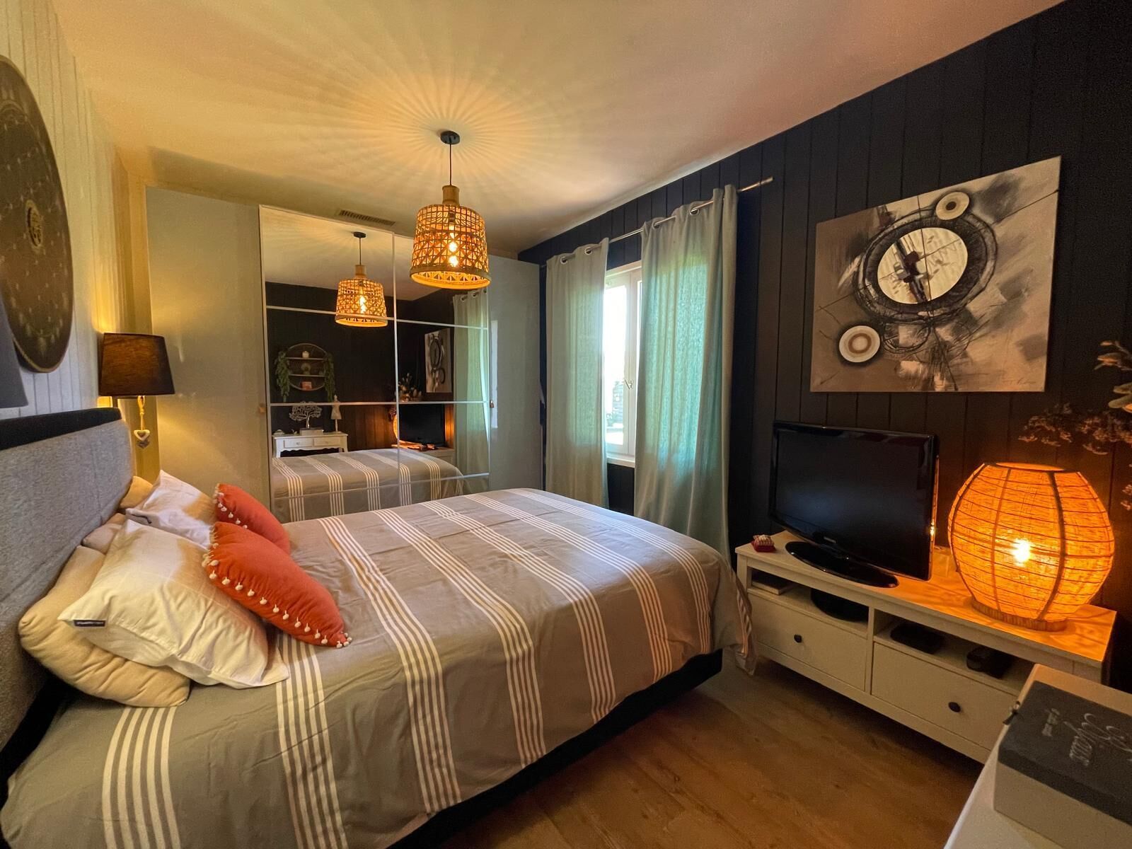A bedroom with a bed, bedside lamps, a TV, and a mirror.