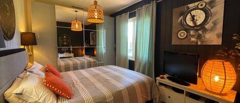 A bedroom with a bed, bedside lamps, a TV, and a mirror.