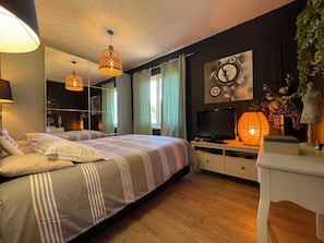 Um quarto moderno com uma cama grande, mesas de cabeceira, uma televisão e um relógio fixado na parede.