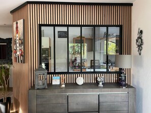 Cozinha moderna com uma janela grande, painéis de madeira e um armário cinza com objetos decorativos.