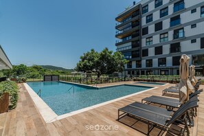 A rooftop pool area with lounge chairs and a building in the background.