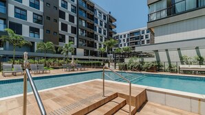 A modern pool area with a clear blue pool, sun loungers, and a staircase leading to the pool. - Cond Apartments Vila do Lago in Jurere - VLO (Florianópolis)