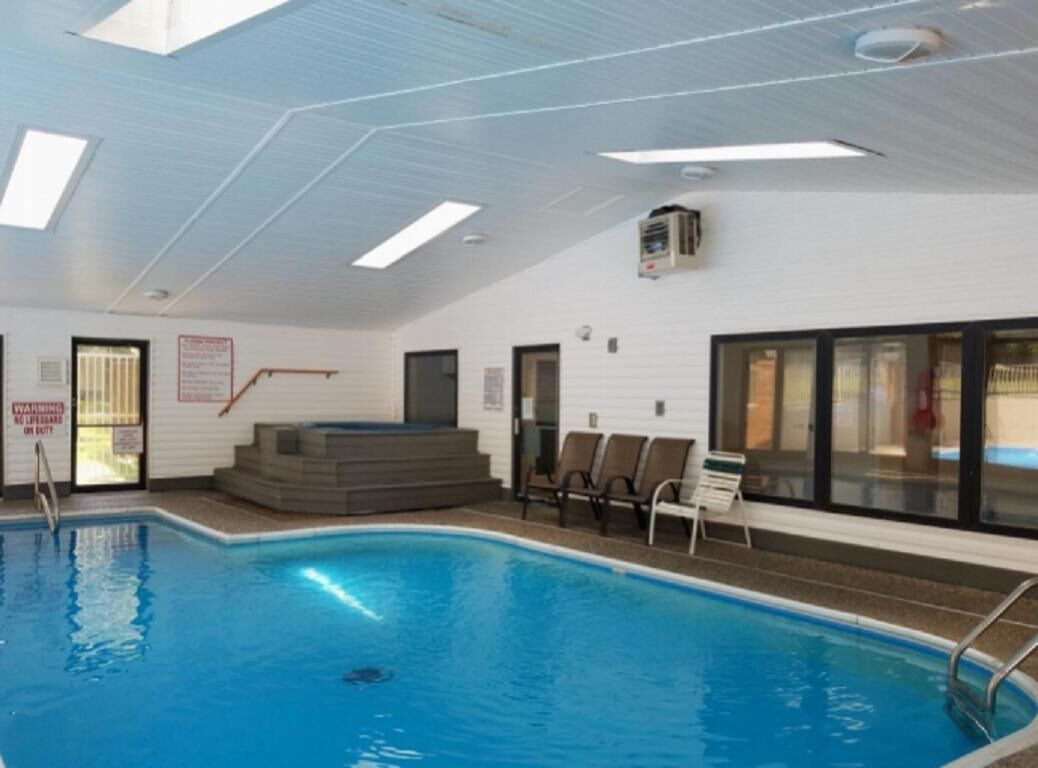 An indoor swimming pool with clear water, a sunroof, and a safety sign.