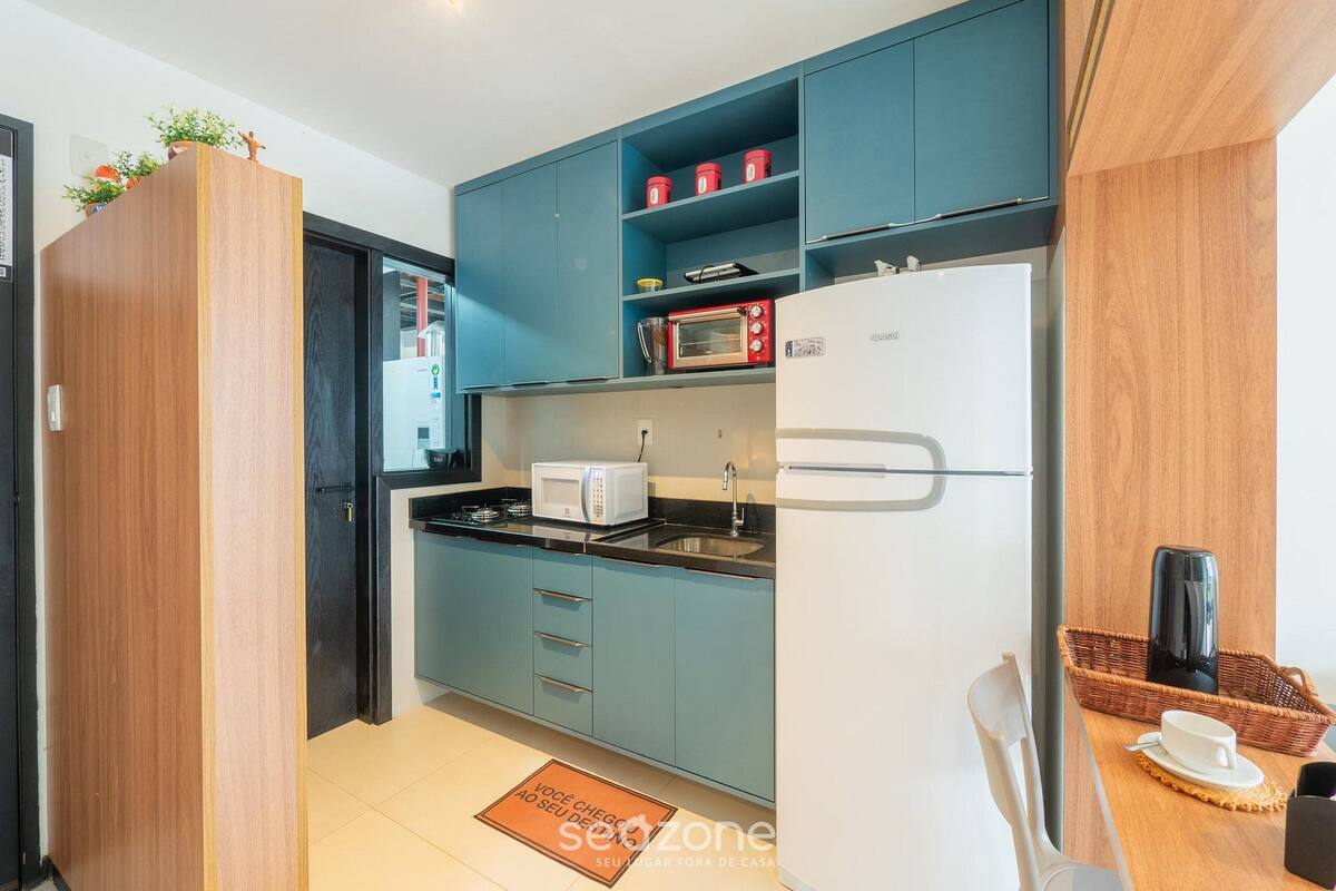 A compact kitchen with teal cabinets, a white refrigerator, a microwave, and a sink.