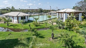 A residential area with a basketball court, small buildings, and a pond. - VLP - Apartments Close to Praia do Forte/ba (Mata de São João)