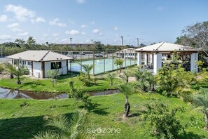 A residential area with a basketball court, small buildings, and a pond. - VLP - Apartments Close to Praia do Forte/ba (Mata de São João)
