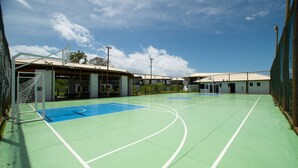 An outdoor basketball court with a net, surrounded by buildings and a clear sky. - VLP - Apartments Close to Praia do Forte/ba (Mata de São João)