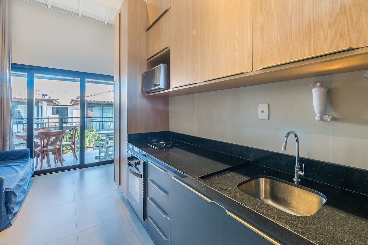A modern kitchen with a black countertop, stainless steel sink, and wooden cabinets.