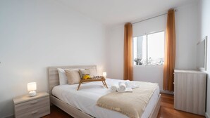 Un dormitorio moderno con cama, mesita de noche y un pequeño armario de madera.