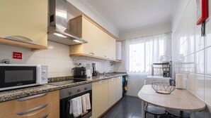 Cocina compacta con microondas, estufa y lavamanos.  Pequeño comedor con mesa y sillas.