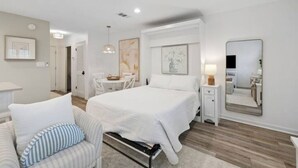 A modern bedroom with a bed, bedside tables, a chair, and a large mirror.