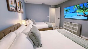 Habitación de hotel con dos camas, televisión y ventilador de techo.