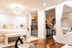 Une chambre à coucher moderne avec un grand lit, des tables de chevet, un banc et un vase décoratif.