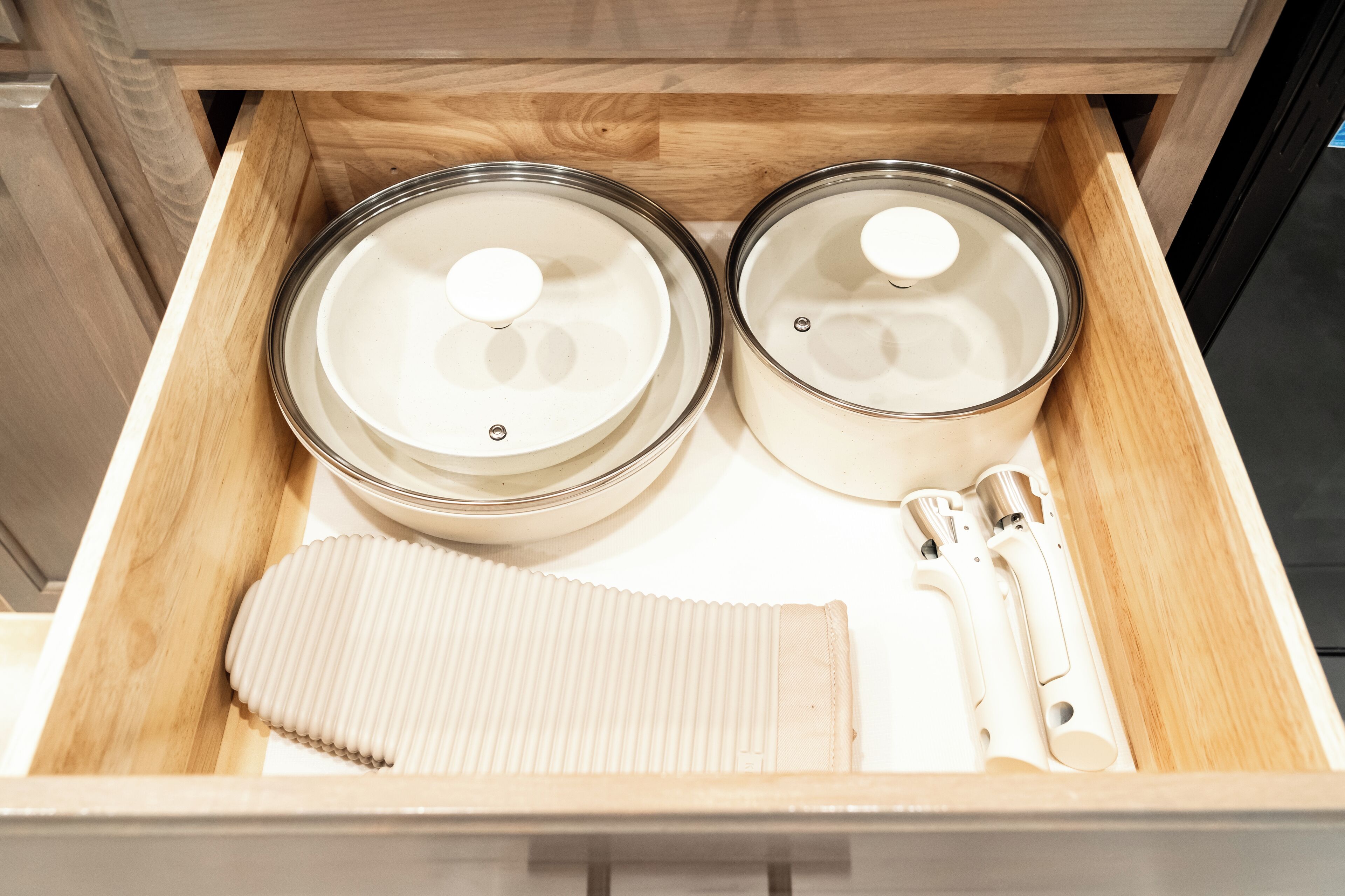 A drawer with two glass jars, a white brush, and a white container.