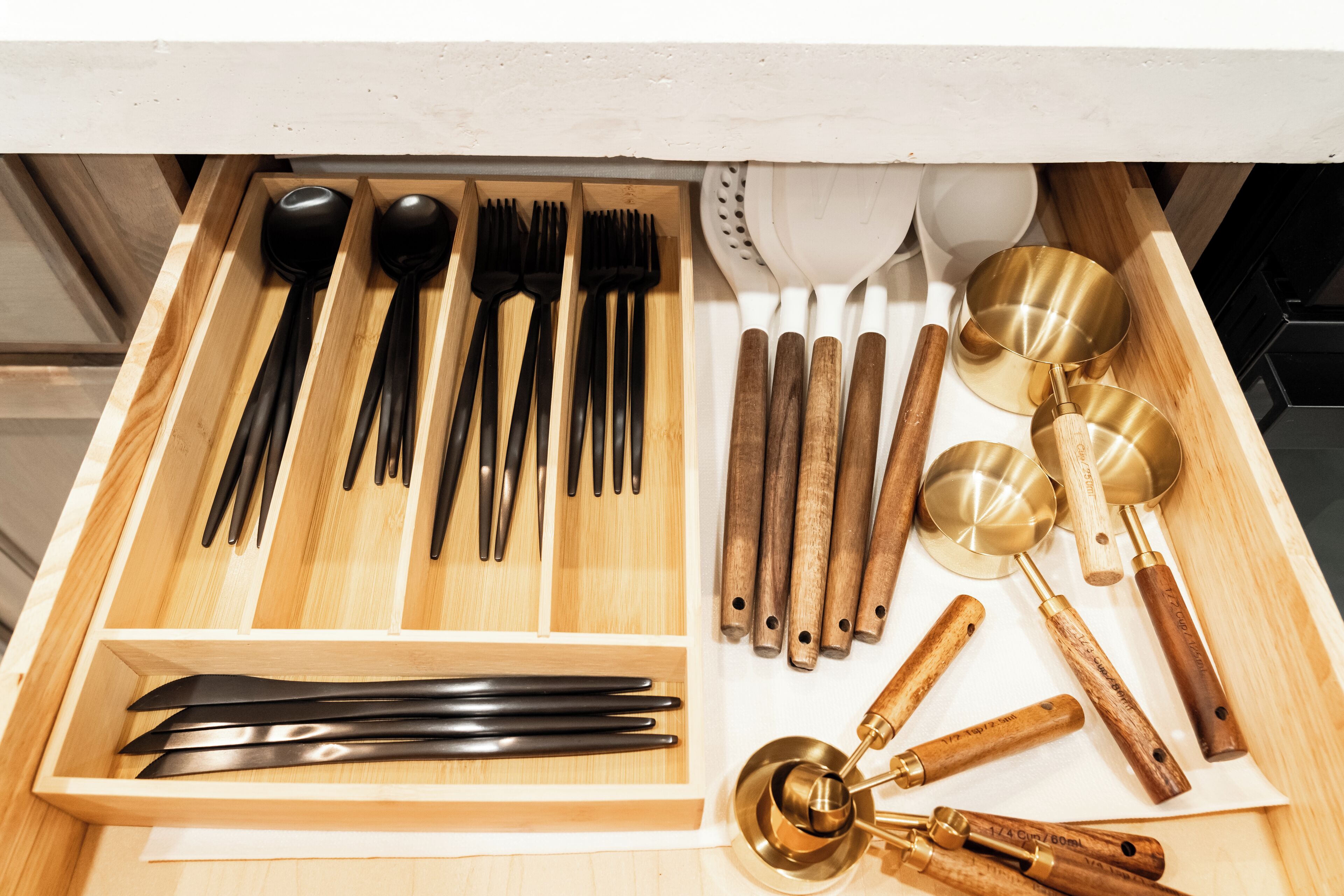 Un cajón con varios utensilios de cocina, incluyendo cucharas, tenedores, cuchillos y cucharones.