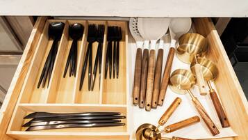 Un cajón con varios utensilios de cocina, incluyendo cucharas, tenedores, cuchillos y cucharones.