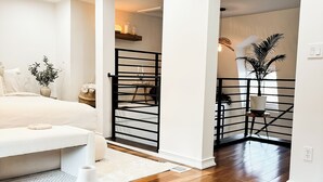 Un dormitorio moderno con cama, mesita de noche y vistas a un balcón con barandilla.