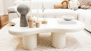Un sofá blanco con una manta beige y un cojín blanco.