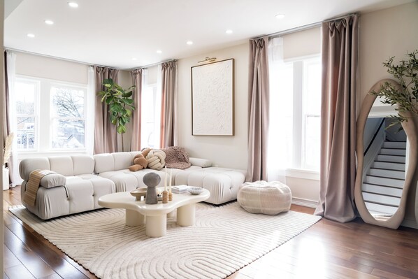 Un salon moderne avec un canapé d’angle, une table basse et une grande plante en pot.