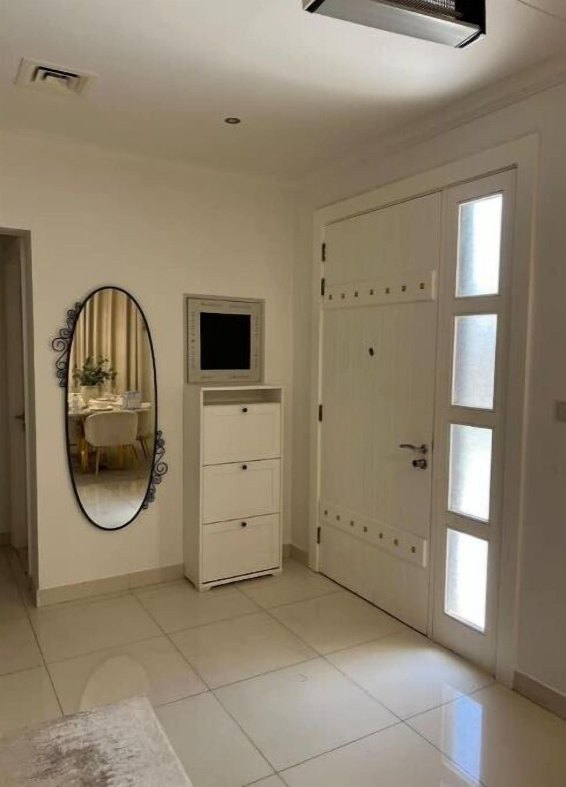 Une pièce avec une armoire blanche, un miroir et un petit téléviseur fixé au mur.