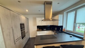 A modern kitchen with a central island, stainless steel appliances, and a large window providing natural light.