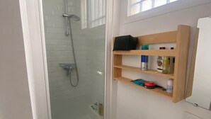 A modern bathroom with a glass-enclosed shower, a wooden shelf with toiletries, and a white bathtub. - Studio Rue Charlot, Marais (quartier marché des enfants rouges) (Paris)