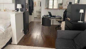 A compact living space with a bed, a sofa, a dining table, and a kitchenette. - Studio Rue Charlot, Marais (quartier marché des enfants rouges) (Paris)