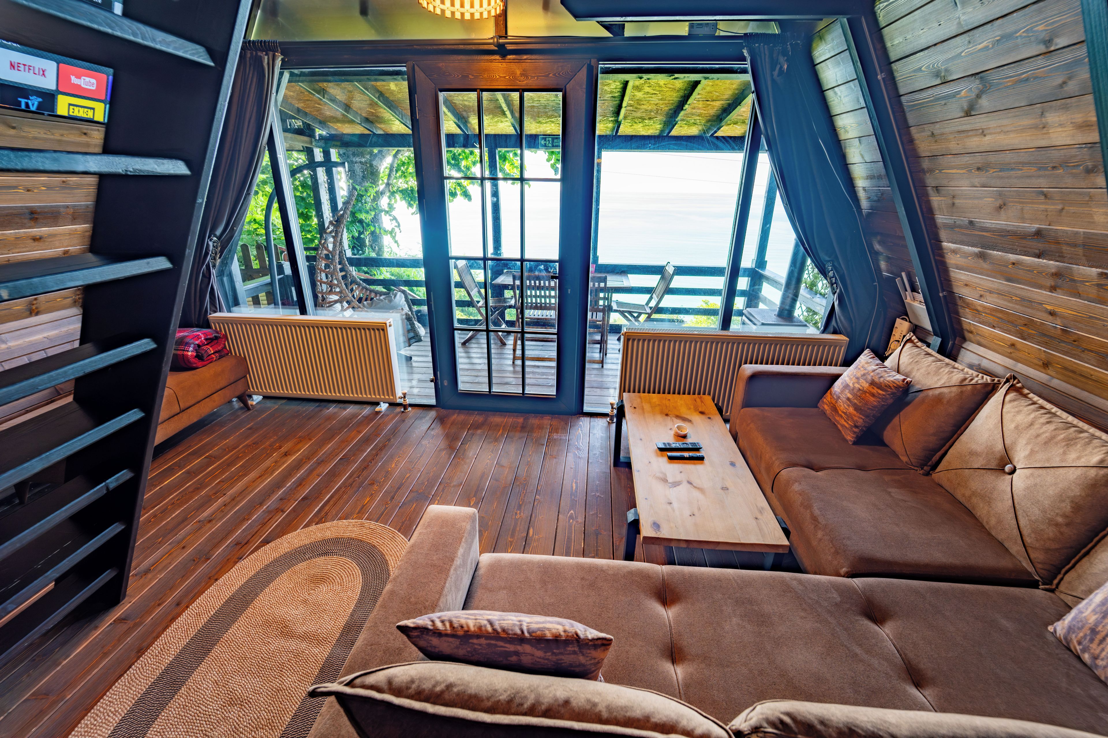 A cozy interior with a sofa, a small table, and a view of the outdoors through a glass door.
