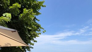 Una terrassa de fusta amb una taula i dues cadires, amb vistes a una massa d'aigua i una riba llunyana.