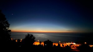 Vistes costaneres a la capvespre amb la silueta d'una vila i un cos d'aigua.