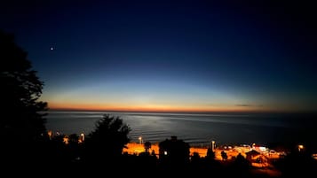 Vista costera al anochecer con el perfil de una ciudad y un cuerpo de agua.