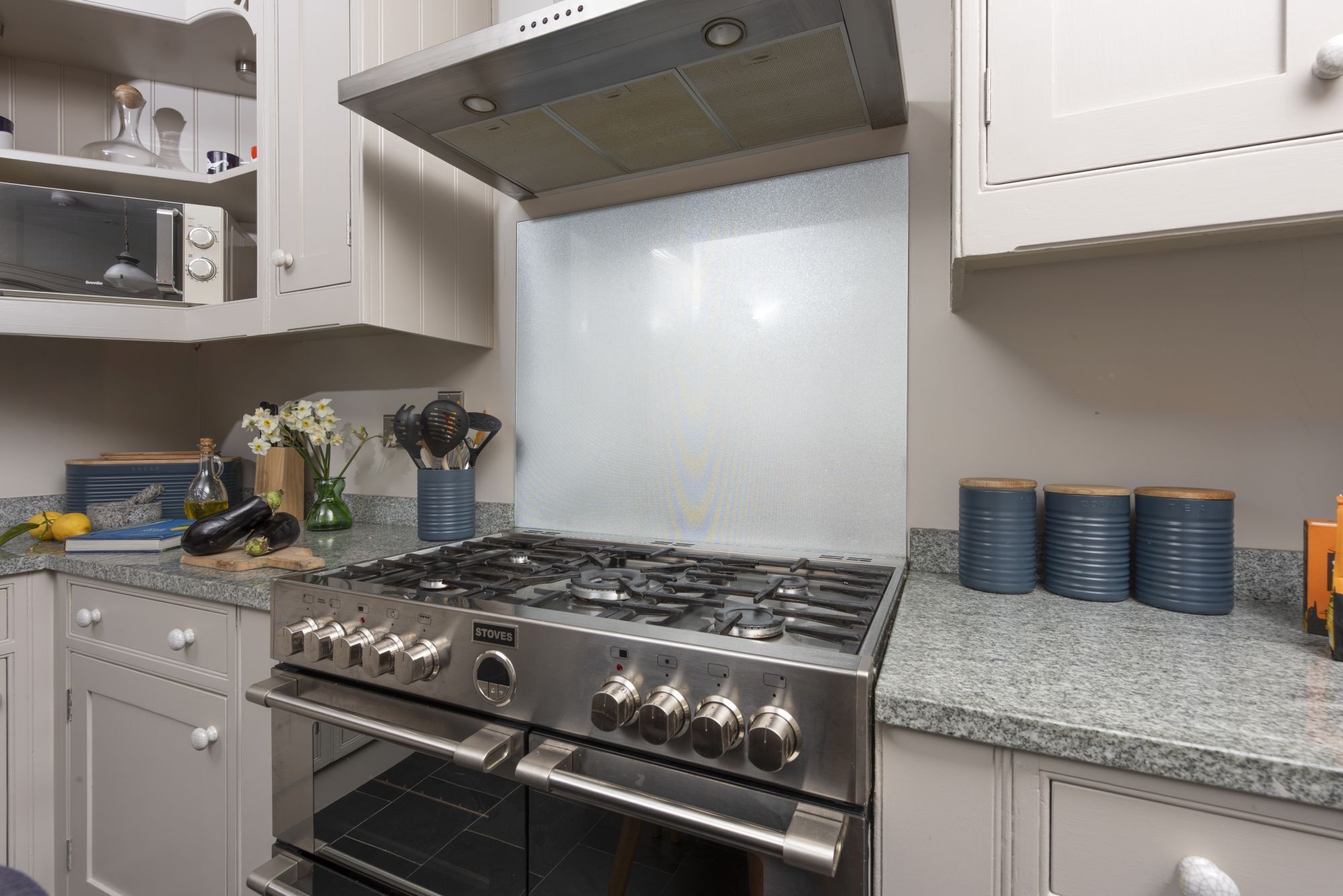 Cucina con piano cottura, forno e microonde in acciaio inossidabile. Sono presenti pensili, un piano di lavoro e una schiena di cucina.