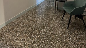 A hallway with a speckled floor, a green chair, a framed picture on the wall, and a small table with a bottle and glass. - The Coccagna Hideaway Secret Whispered in the Alleys (Genova)