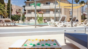 A poolside area with lounge chairs and a checkered board game. - Fiesta Beach Apartments (Sant Llorenc des Cardassar)
