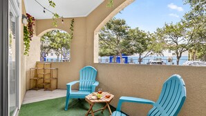 Un balcon avec deux chaises bleues, une petite table en bois sur laquelle sont disposés des fruits et des boissons, et un mur végétal.