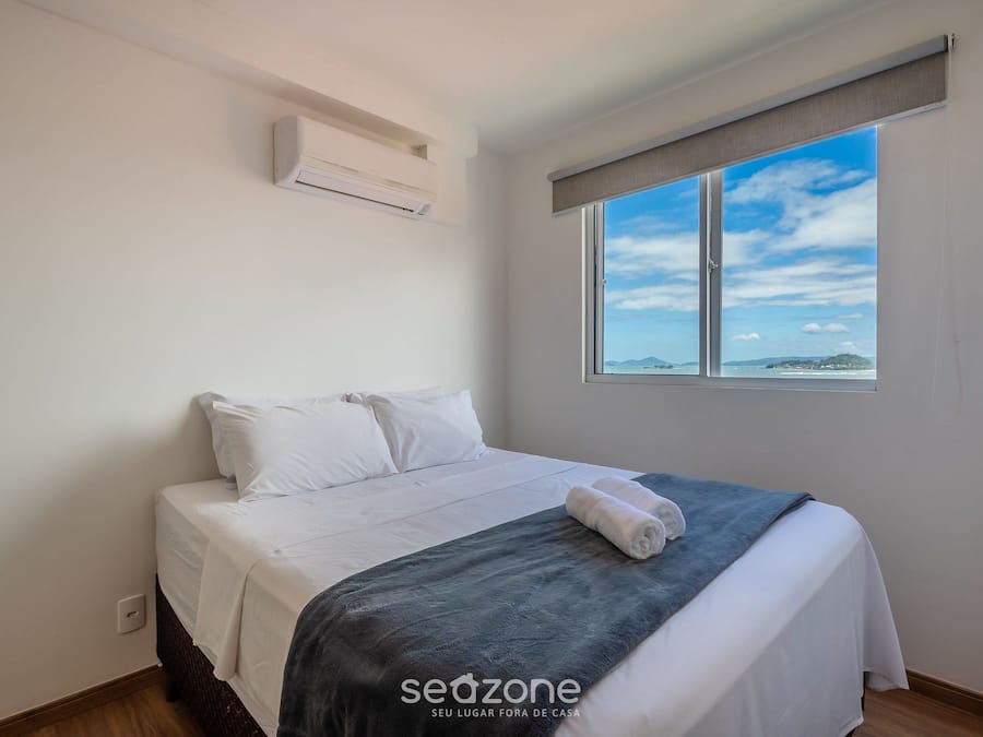 Een slaapkamer met een bed, een raam met uitzicht en een airconditioning.