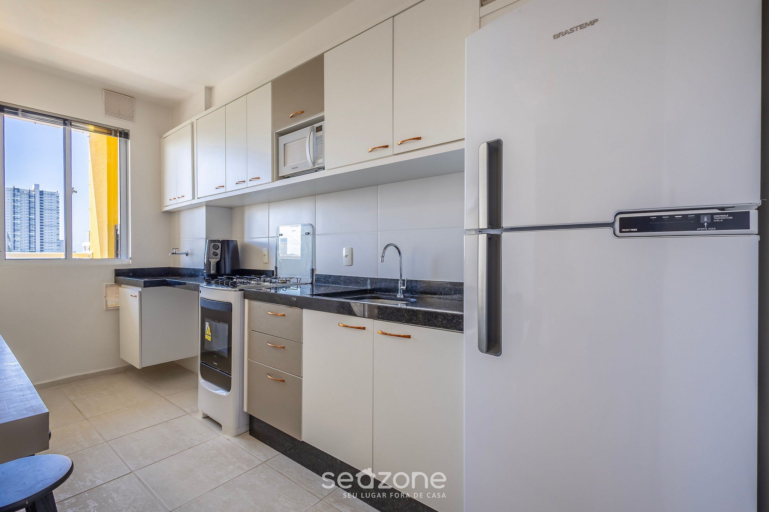A modern kitchen with white cabinets, a stainless steel refrigerator, and a microwave.
