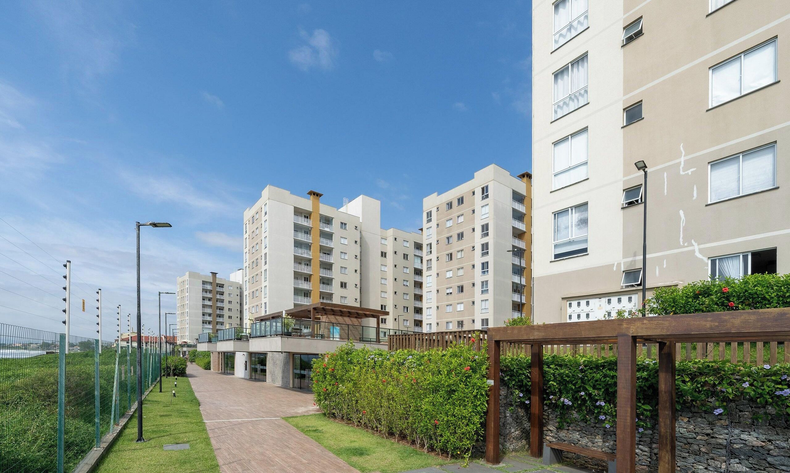 Un conjunto residencial con varios edificios de apartamentos, un camino pavimentado y una pequeña zona cubierta con asientos.