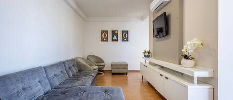 A modern living room with a grey sofa, a white console table, and a flat-screen TV mounted on the wall.