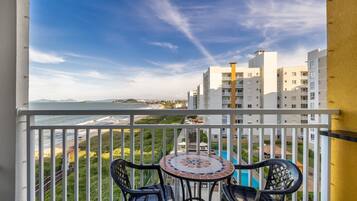 A balcony with a view of the sea, a tiled table, and two chairs.