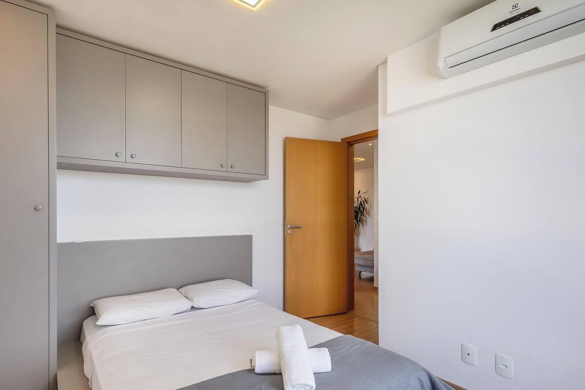 Quarto com cama, guarda-roupa, porta e ar condicionado.