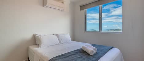 Un dormitorio con cama, ventana con vistas y equipo de aire acondicionado.