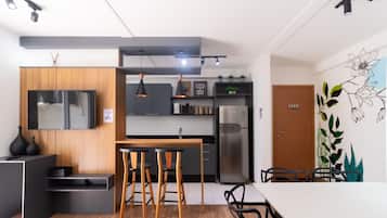Una cocina moderna con horno empotrado, refrigerador y comedor con mesa de madera y taburetes de bar.