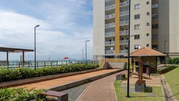 A modern apartment building with a pool area, outdoor seating, and a view of the sea.