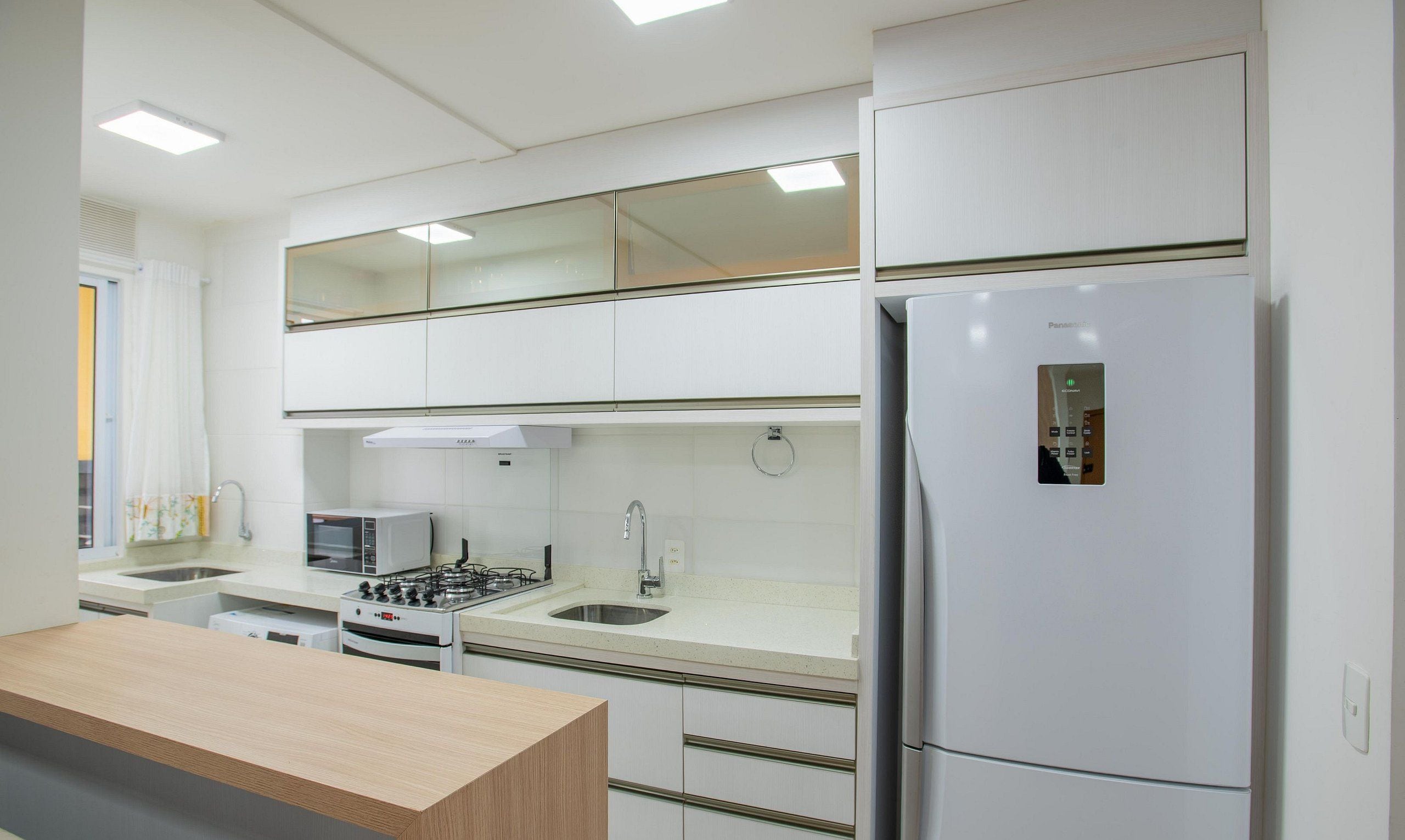 A modern kitchen with a built-in microwave, stove, sink, and refrigerator.