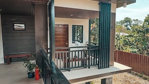 Un espace extérieur abrité, avec un banc en bois, une petite table et une rambarde.