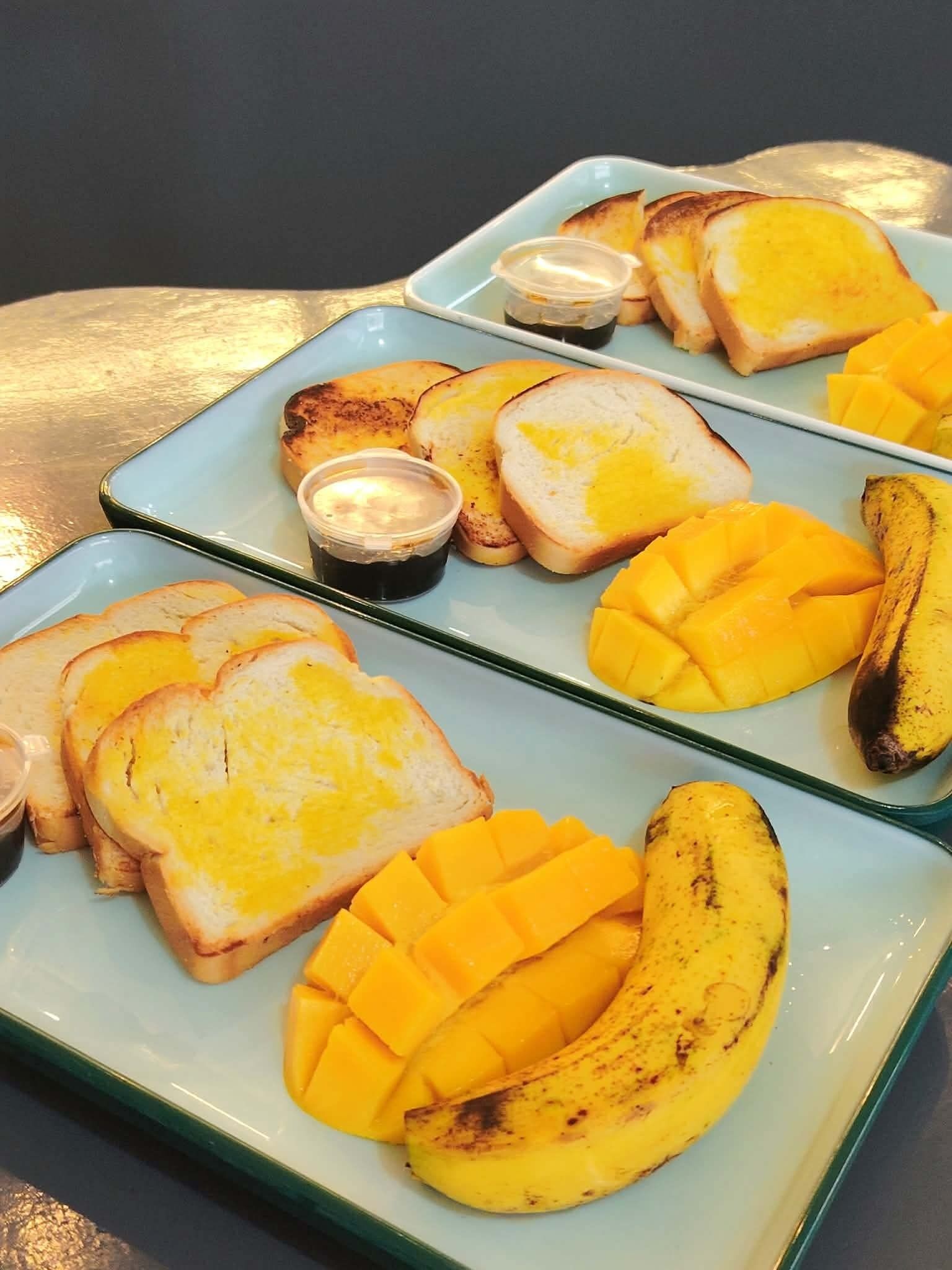 A plate with toasted bread, mango chunks, and a banana.